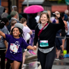 A program participant and running buddy celebrate reaching the finish line at the 5K