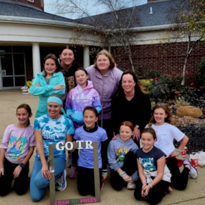 A junior coach poses with her Girls on the Run team 