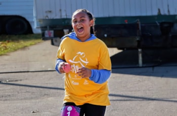 Girls on the Run participant wearing yellow shirt runs the 5K